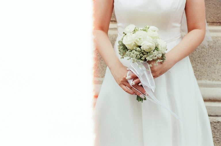 Bride in a wedding dress holding a white rose bouquet, perfect for wedding themes.