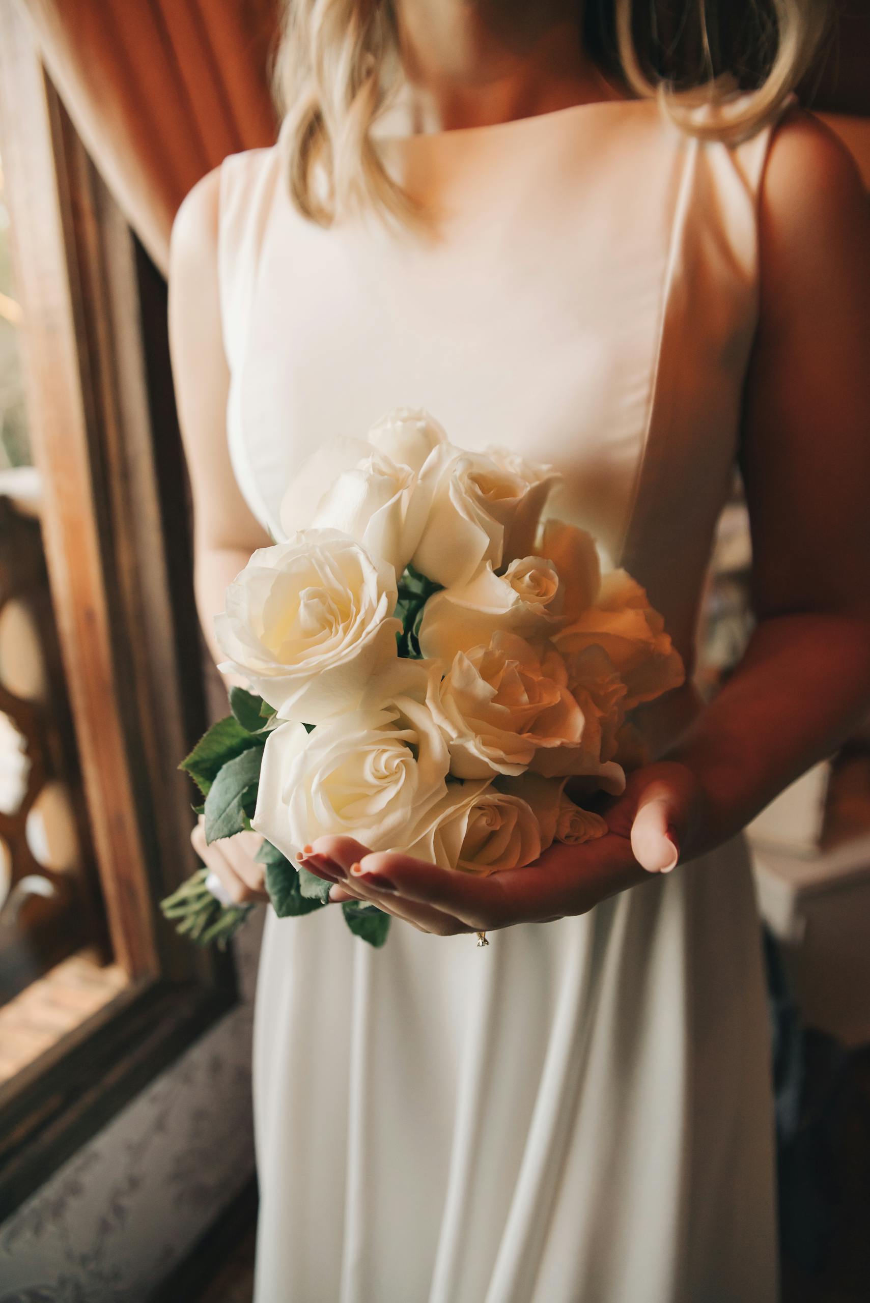 Close-up of a bride holding a white rose bouquet, perfect for wedding themes.